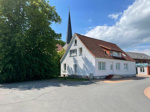 a white house with a church steeple in the background at Apartment Am Ostedeich-2 by Interhome in Oberndorf