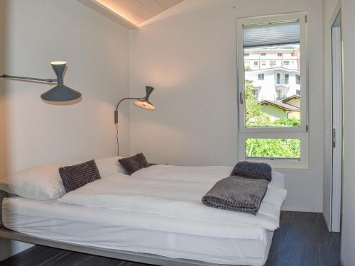 a white bed in a room with a window at Apartment Capriccio 14 Balcony by Interhome in Intragna