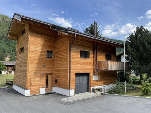 a wooden house with a garage in a parking lot at Apartment Ilse EG by Interhome in Fieschertal