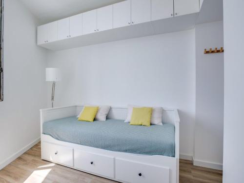 - un lit blanc dans une chambre blanche avec des oreillers jaunes dans l'établissement Apartment Roche Ronde by Interhome, à Biarritz