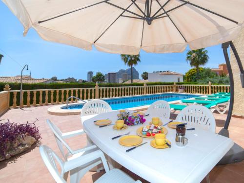 stół z parasolem przy basenie w obiekcie Holiday Home Marie Louise by Interhome w mieście Calpe