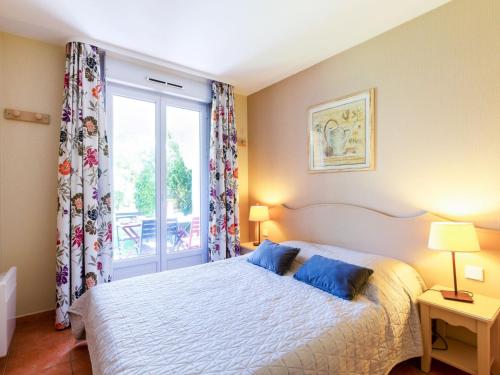 une chambre avec un lit avec des oreillers bleus et une fenêtre dans l'établissement Apartment Domaine VarAzur by Interhome, aux Issambres