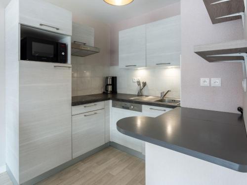 une cuisine avec des armoires blanches et un comptoir noir dans l'établissement Apartment Montjoie- Bat A by Interhome, à Saint-Malo