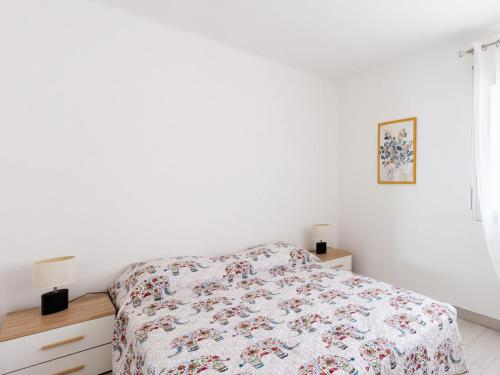 une chambre blanche avec un lit avec un couvre-lit fleuri dans l'établissement Apartment Les Trois Caps by Interhome, à Cagnes-sur-Mer