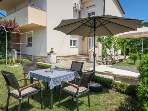 a table and chairs with an umbrella in the yard at Apartment Mira by Interhome in Rab