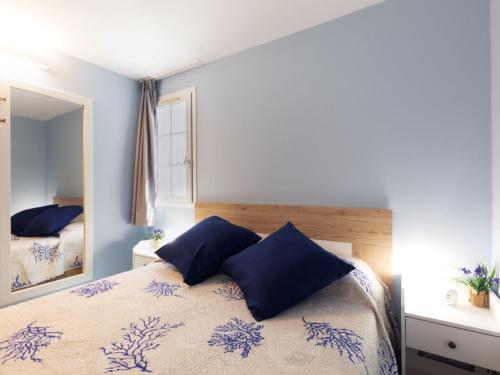 une chambre avec un lit avec des oreillers bleus et un miroir dans l'établissement Apartment L'Esquinade - F6 019 by Interhome, à Saint-Raphaël
