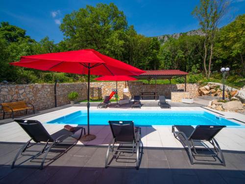 a pool with two red umbrellas and chairs next to a pool at Holiday Home Olivia by Interhome in Bribir