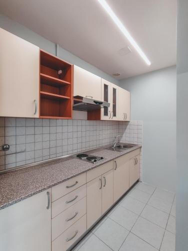 a kitchen with white cabinets and marble counter tops at Motel Almy in Zenica