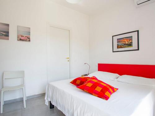 a white bed with a red headboard and a red pillow at Apartment More e Lamponi by Interhome in Avane