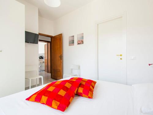 a white bed with a red and yellow checkered pillow at Apartment More e Lamponi by Interhome in Avane