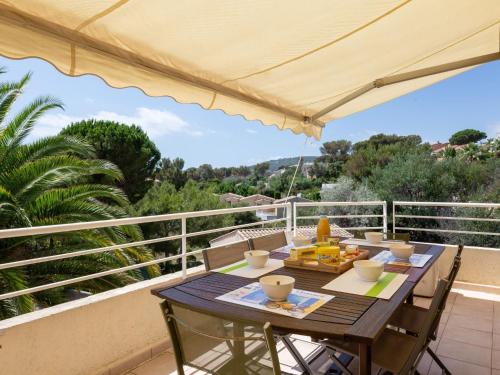 - une table sur un balcon avec un parasol dans l'établissement Apartment Les Mas de la Mer-4 by Interhome, à Saint-Aygulf