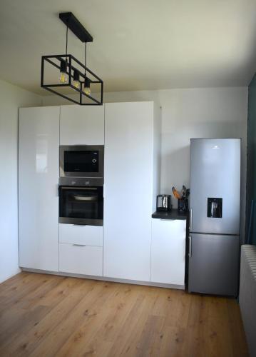  La cuisine est équipée de placards blancs et d'un réfrigérateur. dans l'établissement À 2mn de la plage, maison avec grand terrain clos, à Plérin