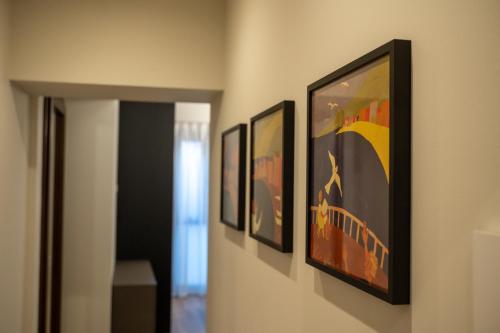 a hallway with four framed paintings on a wall at Palazzo Bellocchi - Suites & Apartments in Brindisi