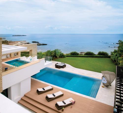 an aerial view of a house with a swimming pool and the ocean at Cap St Georges Villas in Peyia