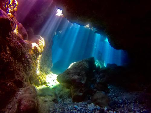 an underwater view of a cave with the sun illuminating the water at Moon's Diving House in Green Island