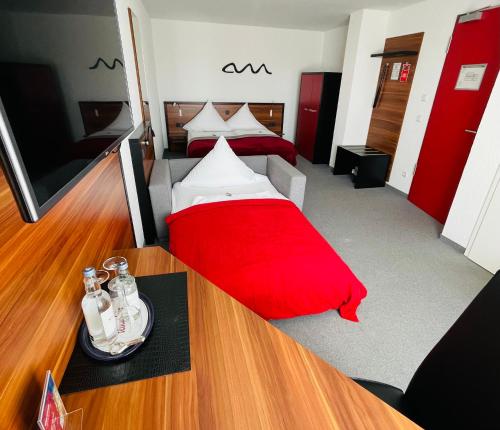 a room with two beds and a red pillow on a table at Allgäuhotel Memmingen Nord in Memmingen