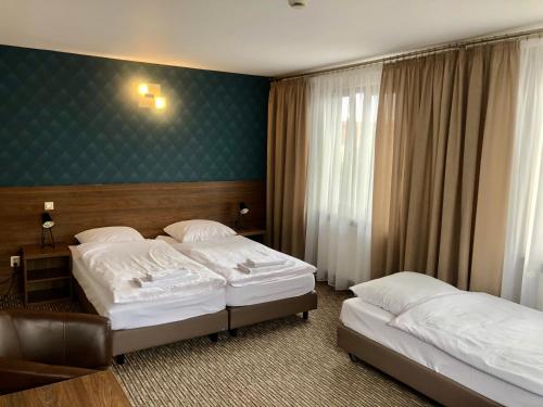 a hotel room with two beds and a green wall at Hotel Krystyna in Szczytno