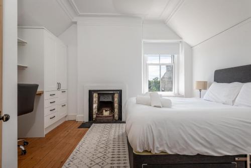 een witte slaapkamer met een groot bed en een open haard bij Oakwood House - Sleeps 6 - St Andrews in St Andrews