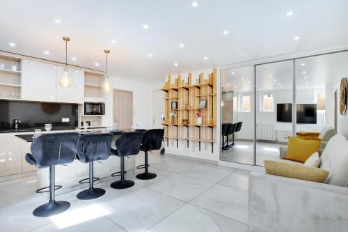 une cuisine et un salon avec des tabourets de bar noirs dans l'établissement Cosy apartment 4P-1BR Flandre-Crimée, à Paris