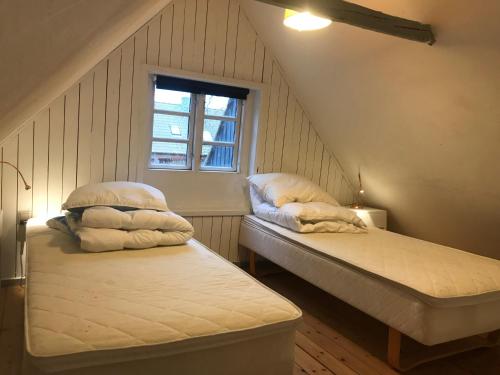 フレデンスボーにあるJulieanehåbのベッド2台と窓が備わる屋根裏部屋です。
