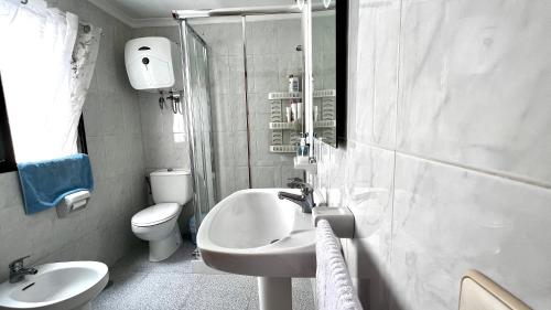 een witte badkamer met een wastafel en een toilet bij Central, quiet and comfortable room, breakfast in Las Palmas de Gran Canaria