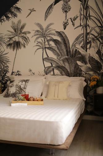 a bedroom with a white bed with palm trees on the wall at B&B Les Lumières in Salerno