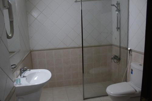 a bathroom with a shower and a toilet and a sink at Caesar Palace in Al Ghurayfah