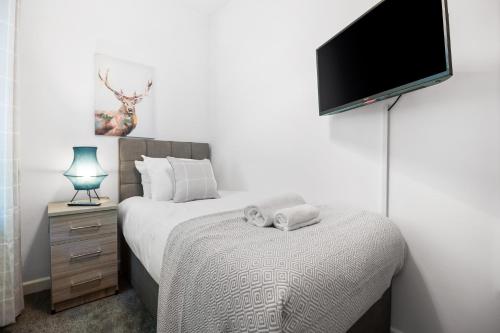 a bedroom with a bed and a flat screen tv at 3 Triple Rooms - Parking - Smart TVs - Work Stays in Swansea