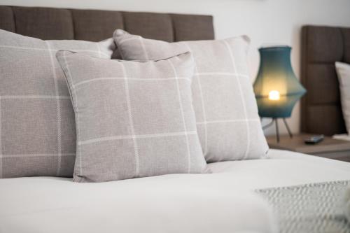 a bed with white pillows and a table with a lamp at 3 Triple Rooms - Parking - Smart TVs - Work Stays in Swansea