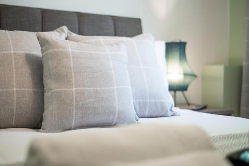 a bed with white pillows and a lamp on a table at 3 Triple Rooms - Parking - Smart TVs - Work Stays in Swansea