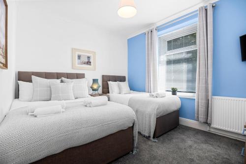 two beds in a bedroom with blue walls and a window at 3 Triple Rooms - Parking - Smart TVs - Work Stays in Swansea