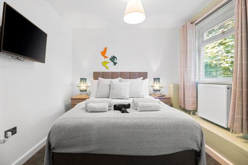 a bedroom with a large bed and a flat screen tv at 3 Triple Rooms - Parking - Smart TVs - Work Stays in Swansea