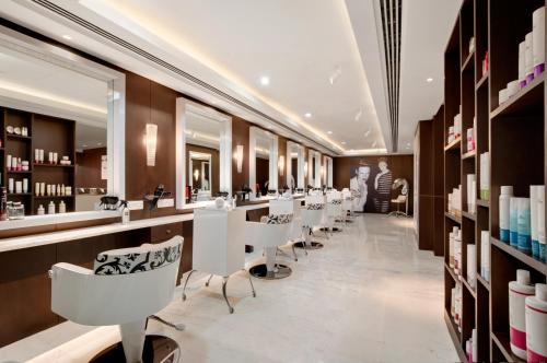 a salon with a row of white chairs and mirrors at The Leela Ambience Convention Hotel Delhi in New Delhi