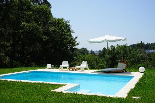 a swimming pool with two chairs and an umbrella at Quinta do Vale Grande in Albergaria-a-Velha