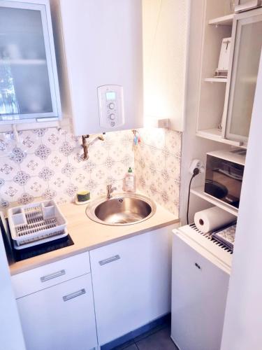 une petite cuisine avec un évier et un micro-ondes dans l'établissement La dune blanche d'Arcachon, à Arcachon