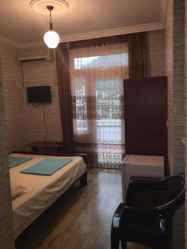 a bedroom with a bed and a chair and a window at Guest House Roman/Gonio in Gonio