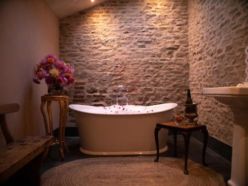 a bath tub in a room with a brick wall at Country Cottage with Spa, Catering, Gardens, Nature Reserve Walks - Free Parking, Self Checkin in Scunthorpe