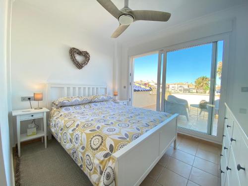 a white bedroom with a bed and a balcony at Dúplex Amparo Altaona Golf in Murcia