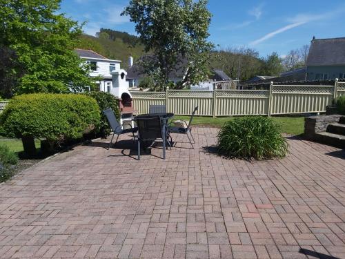 a patio with chairs and a table and a fence at Llys Bach Apartment at Llys Aeron in Aberaeron