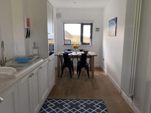 a kitchen with a table and chairs and a window at Porth Colmon in Pistyll