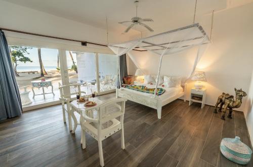 a bedroom with a canopy bed and a table and chairs at Diamonds Mapenzi Beach - All Inclusive in Kiwengwa