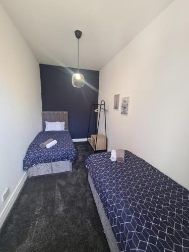 sypialnia z 2 łóżkami i niebieską ścianą w obiekcie 5 bed sleeps 6, 2 miles (7 mins) from city centre w mieście Low Team