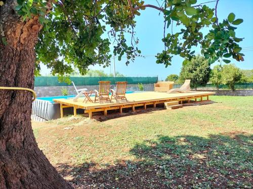 een picknicktafel en twee stoelen naast een boom bij La Casa di Ludovica, Punta della Mola in Siracusa