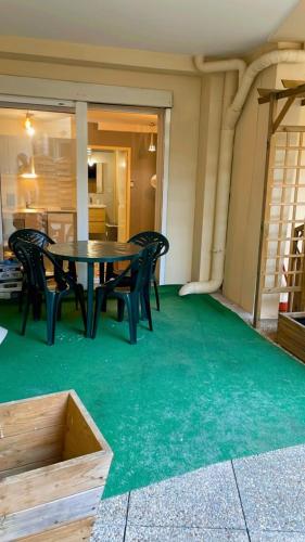 - une table et des chaises sur une terrasse dotée d'une moquette verte dans l'établissement Plénitude terrasse, au Mans