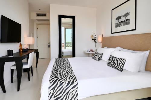 Schlafzimmer mit einem großen weißen Bett, einem Schreibtisch und einem TV in der Unterkunft Mondial Resort & Spa in Marina di Pietrasanta