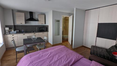 Una habitación con una cama y una mesa y una cocina. en Myappartepinal, en Épinal