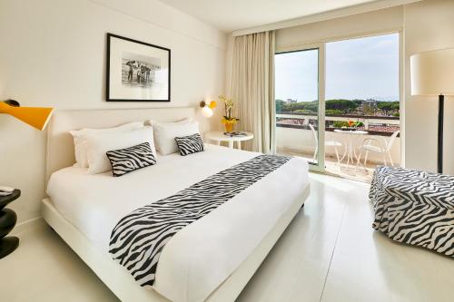 a white bedroom with a zebra print bed and a balcony at Mondial Resort & Spa in Marina di Pietrasanta