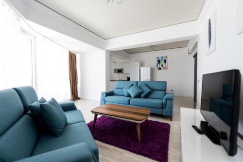 sala de estar con sofá azul y mesa en White Tower Mamaia Apartament Privat 503, en Mamaia
