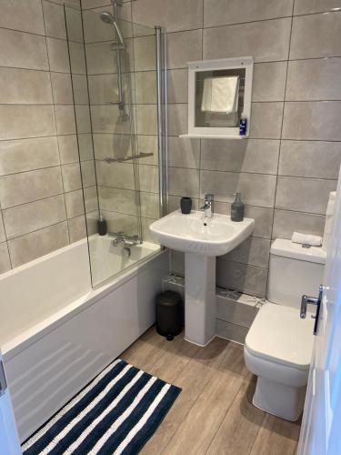 a bathroom with a sink and a toilet and a shower at Penthouse Apartment with seaviews in Walton-on-the-Naze