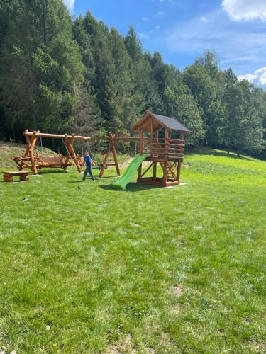 uma criança a brincar num parque com um parque infantil em Chata Lipie 105 em Gródek Nad Dunajcem